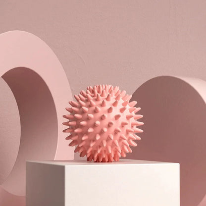 Pink spiky massage ball for muscle relief on a pedestal with abstract background