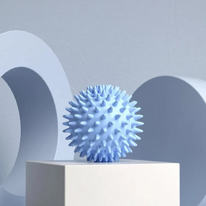 Light blue spiky massage ball for muscle relief on a minimalist pedestal background.